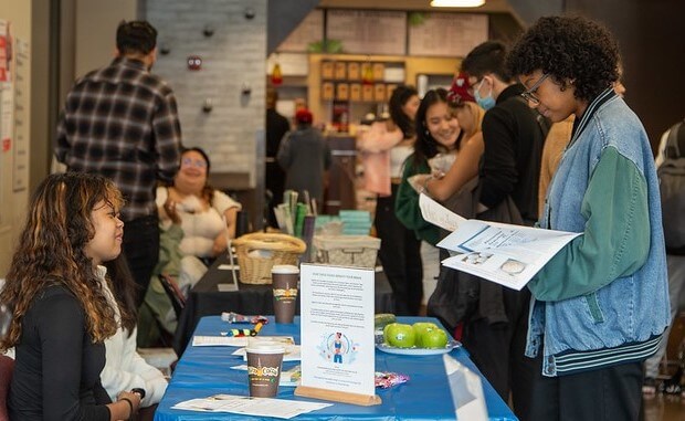 student takes flyer from a table at the health fair