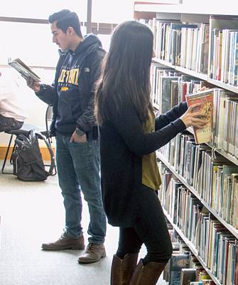 students reading in book stacks in the library
