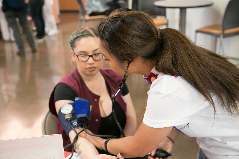 an allied health student takes oxygen measurement of another student