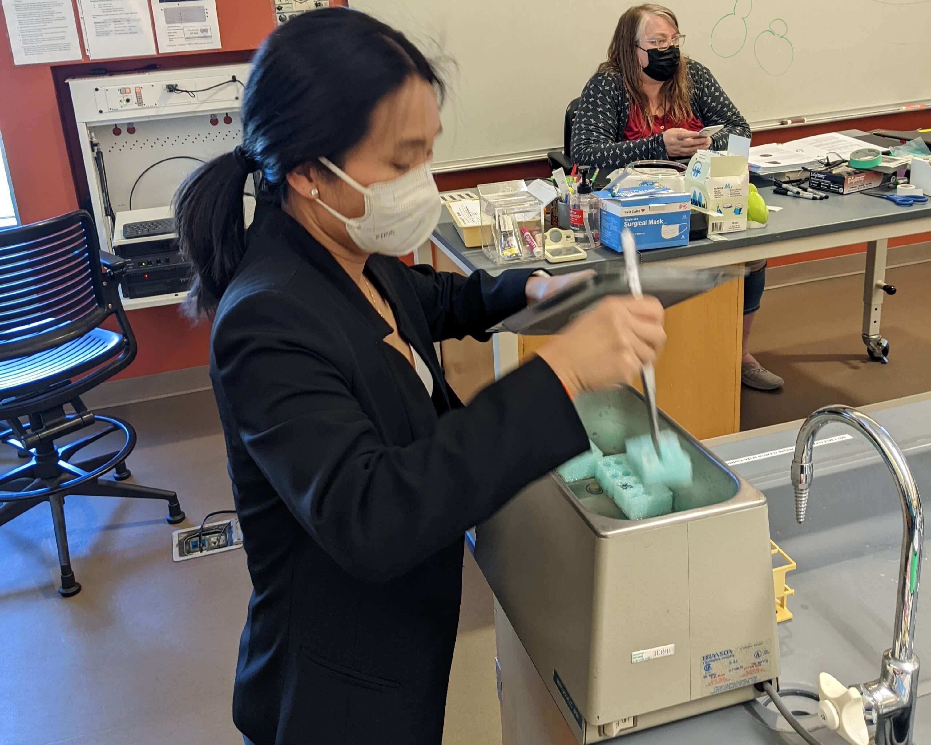 A faculty member preps a machine in a classroom