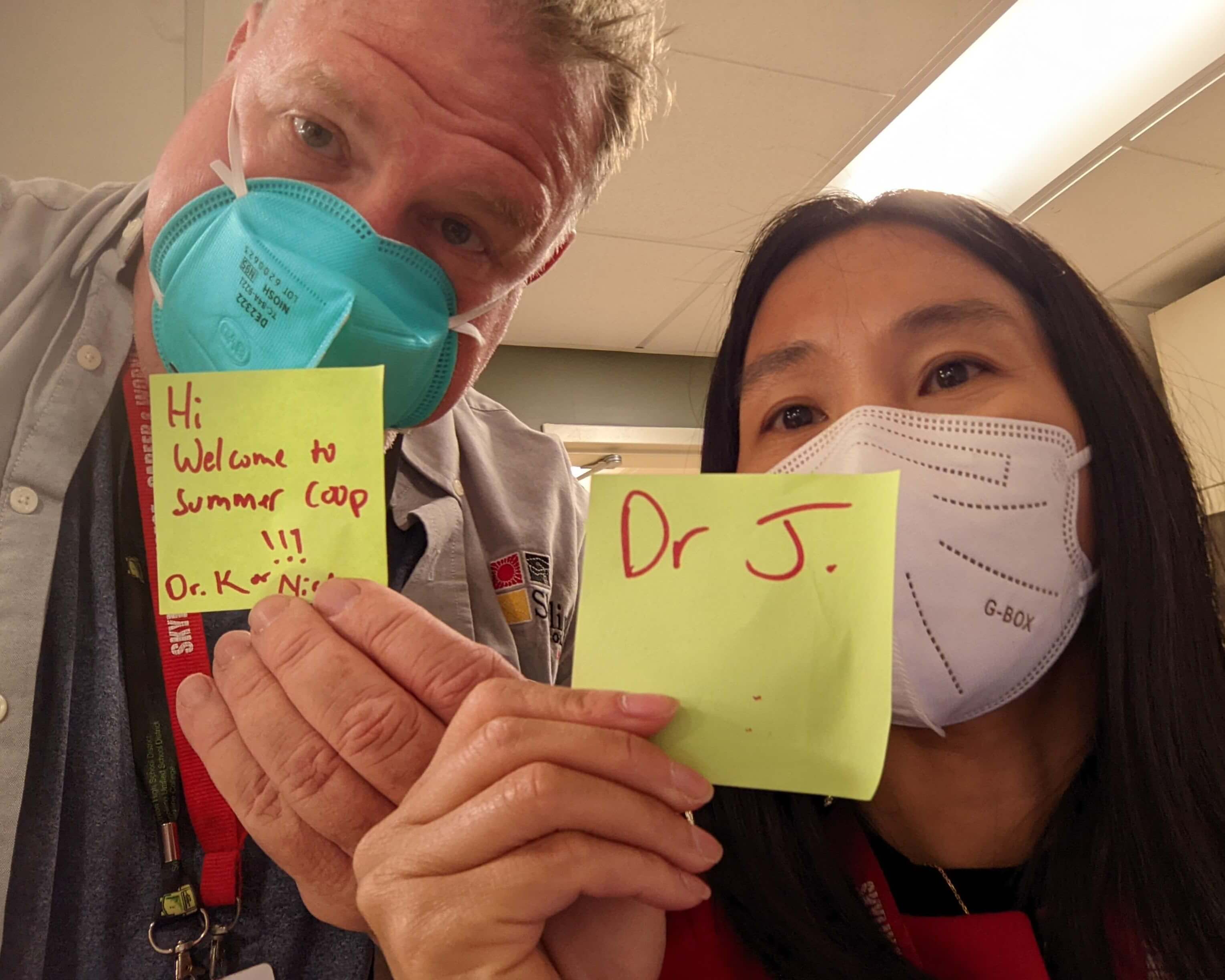 Faculty hold up sticky notes with their names on them for summer camp introductions