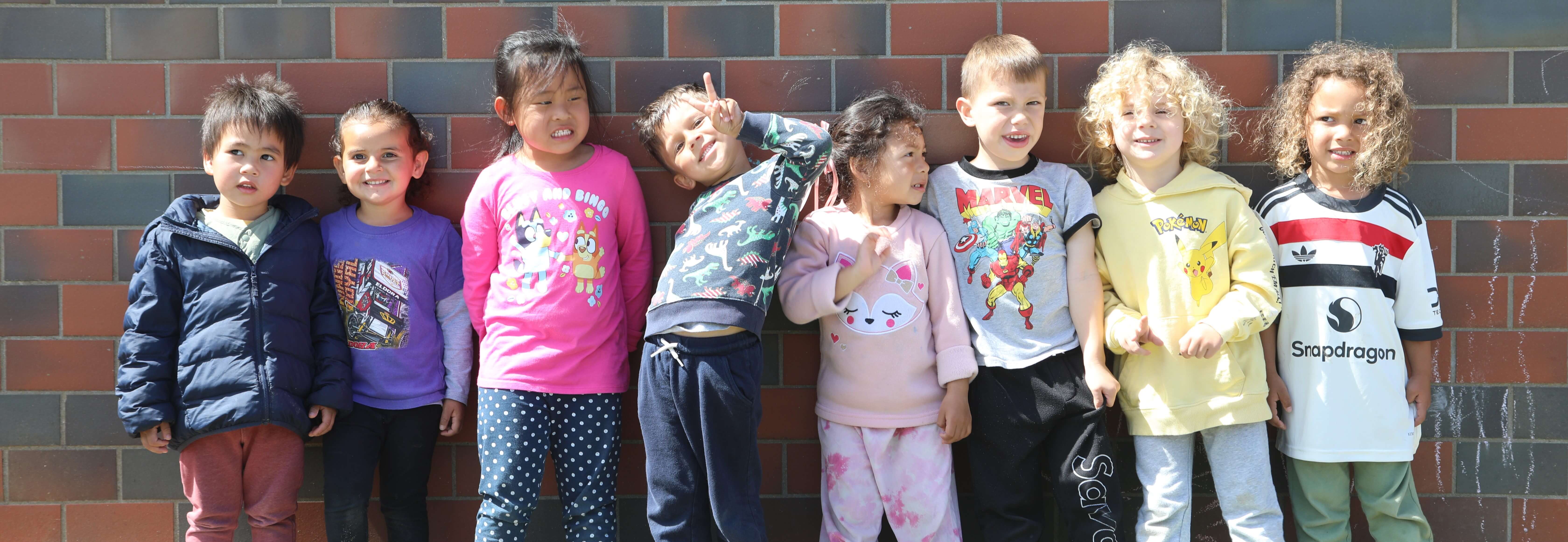 early childhood education students stand together in front of a brick wall