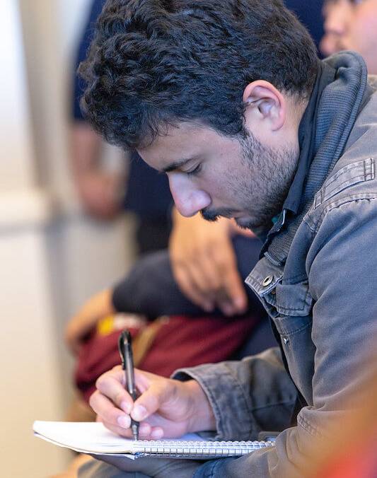 student takes notes in a notebook