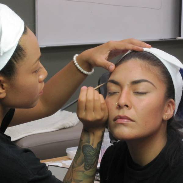 a cosmetology student puts mascara on a client