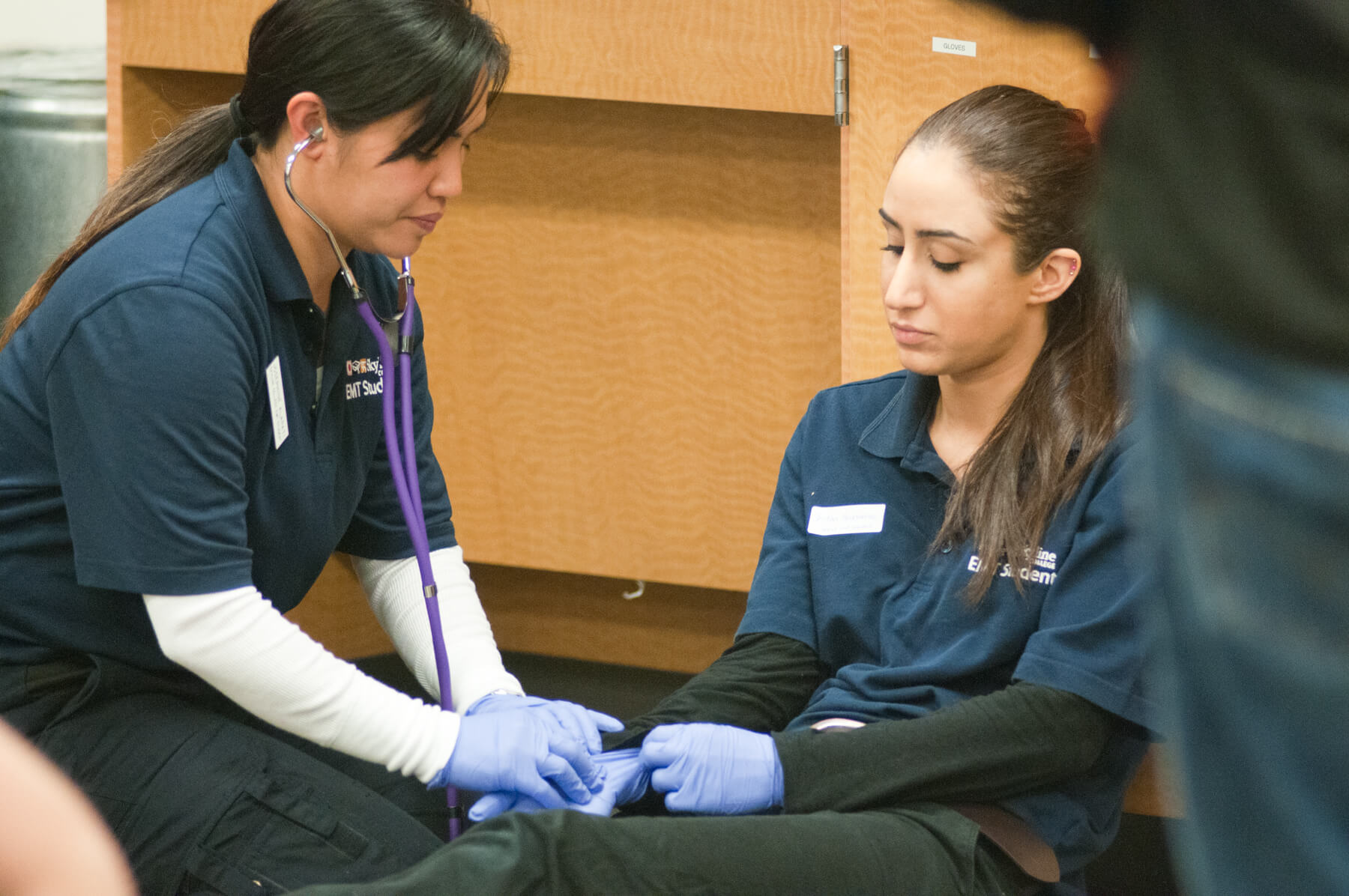 an EMT student practices taking a pulse on another EMT student