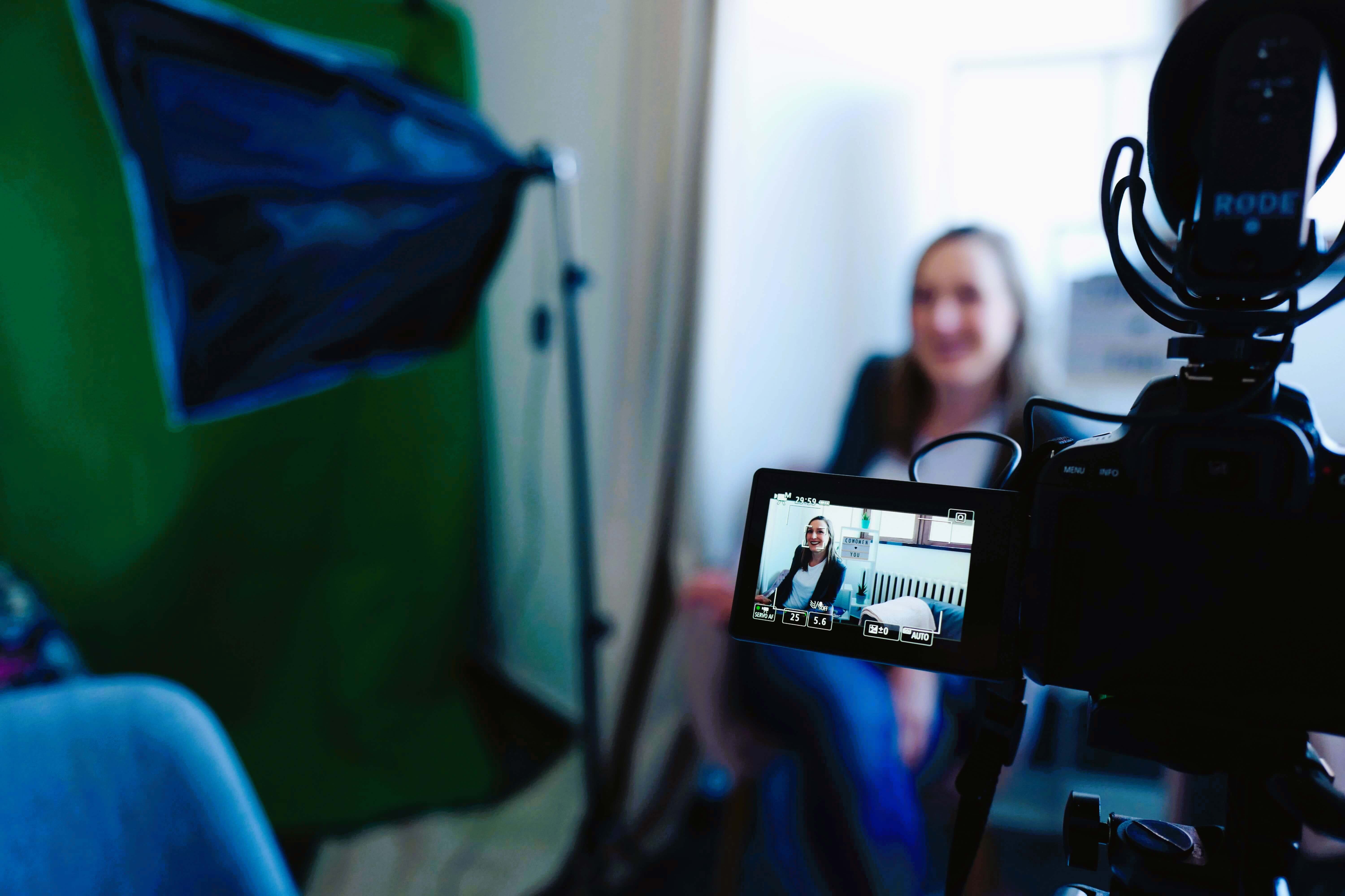 a woman in professional clothing is filmed in an interview setting