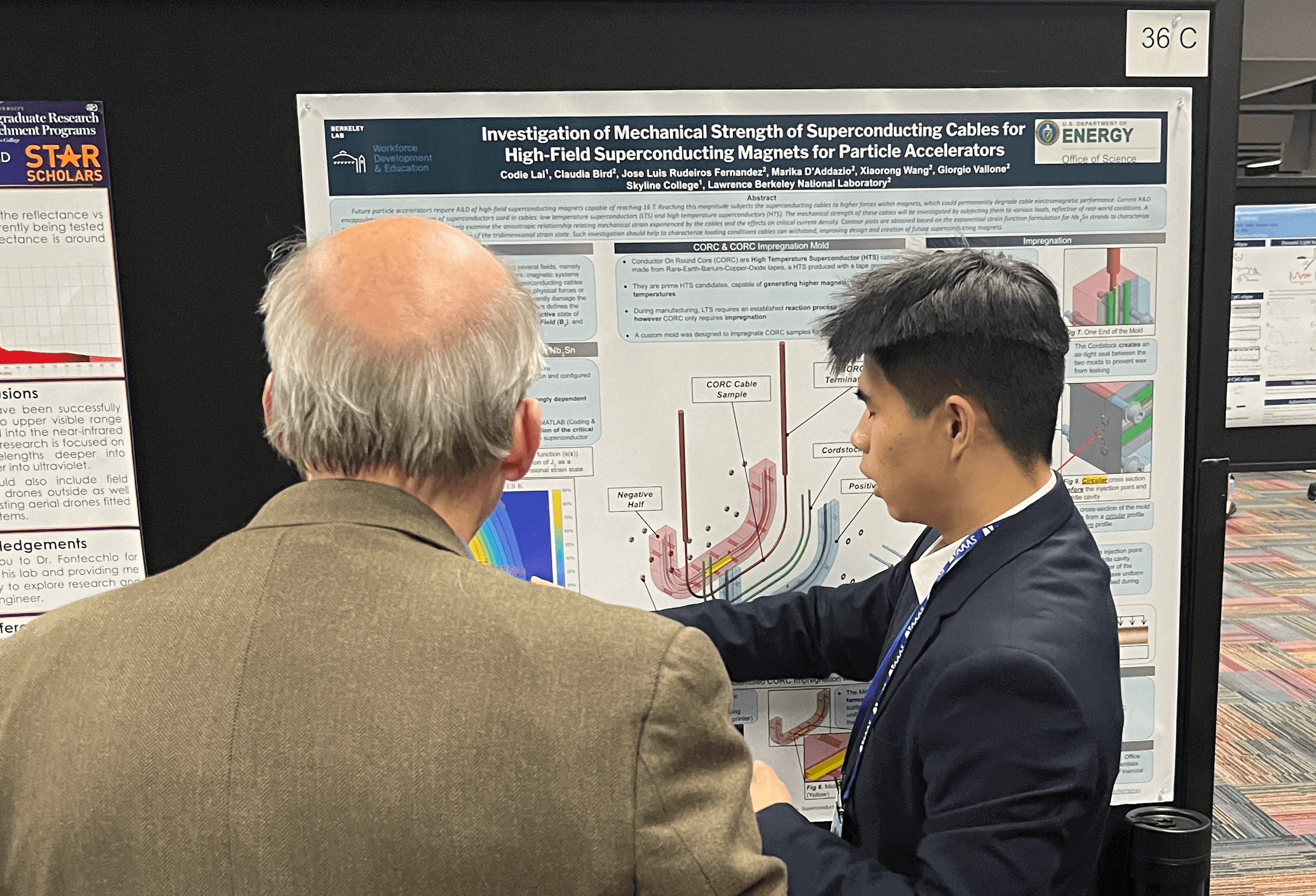 IMMERSE student shows his poster presentation to a person at a conference