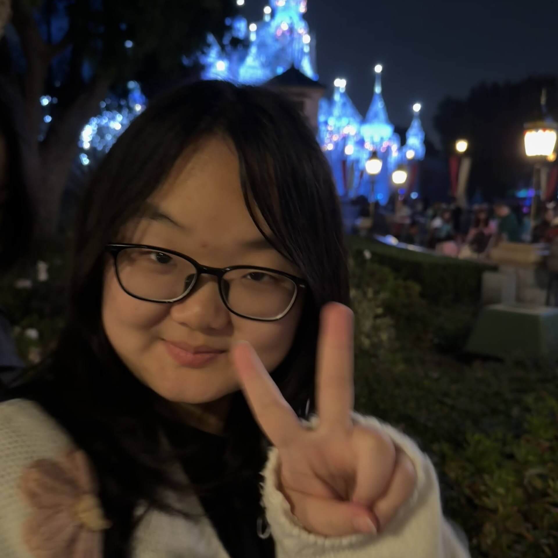 Casual Selfie of Jiaxuan with a peace sign in front of a lit-up Disney Castle