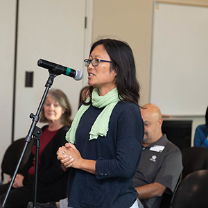 an employee speaking into a mic at an Accreditation forum
