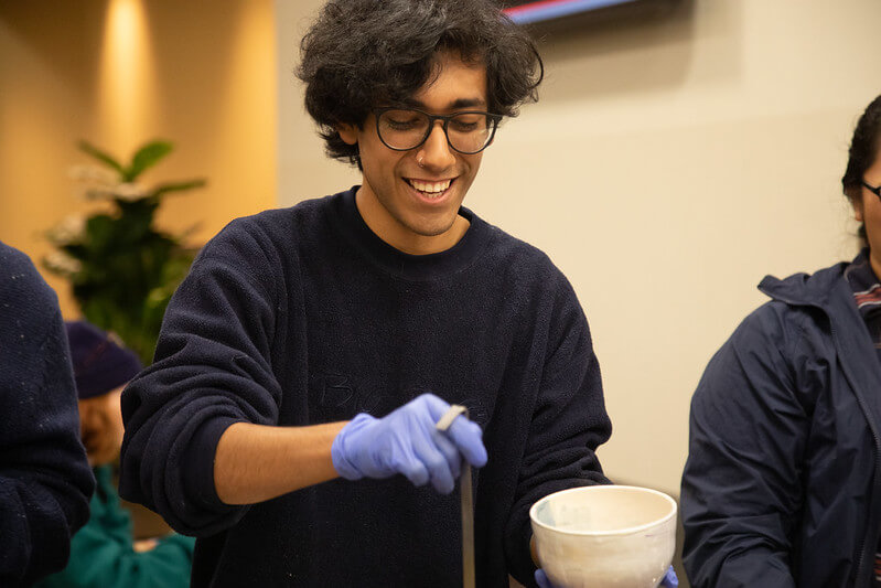 A volunteer with a ladle serving food at the Empty Bowls Fundraiser