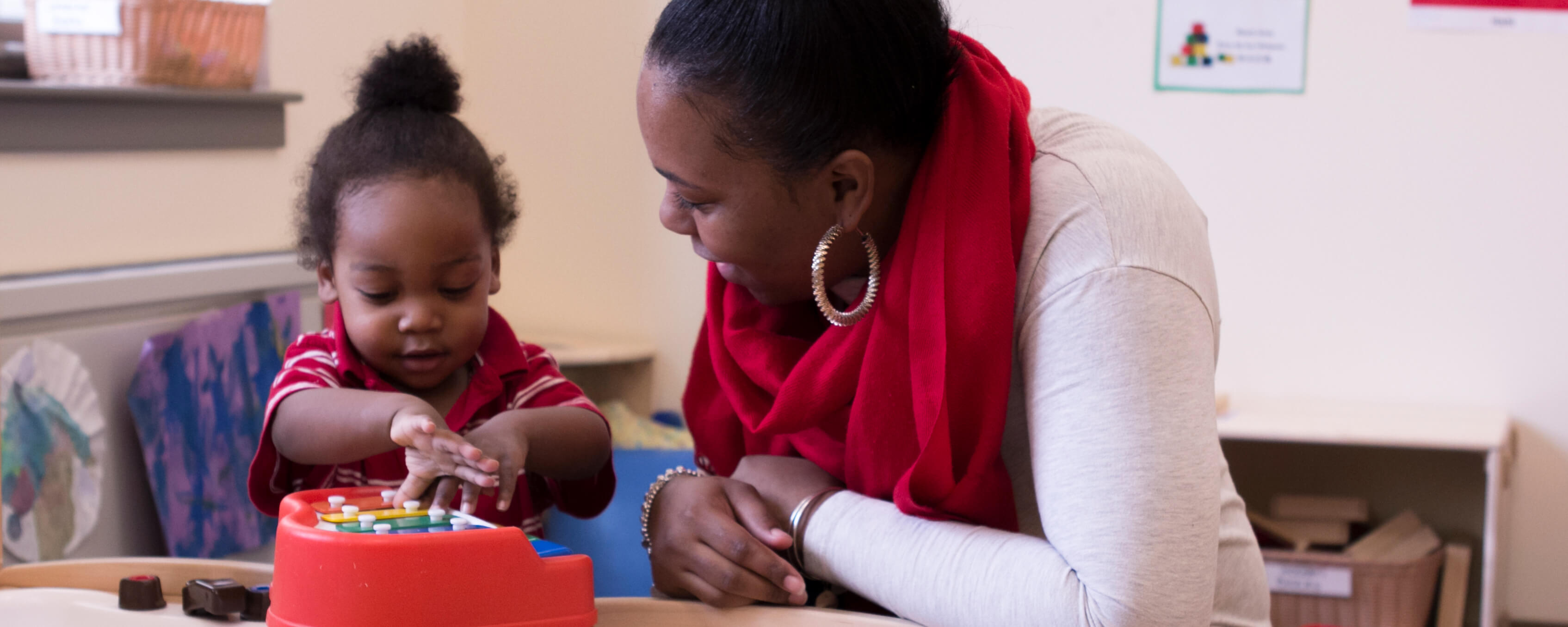 young teacher sits on the floor and plays blocks with young children