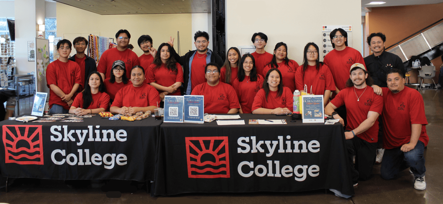 group photo of ASSC posing in matching red shirts at a logomarked Skyline College table